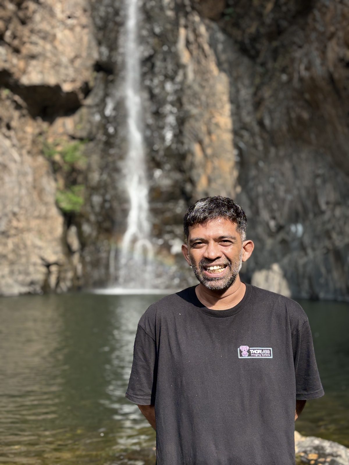 Supreeth smiling in front of a waterfall in the Western Ghats
